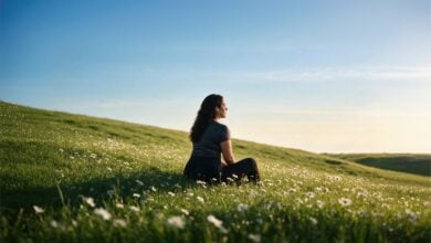 Woman sitting in a meadow beneath a broad sky