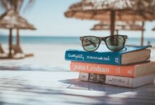Libros y gafas de sol junto a una escena de viaje