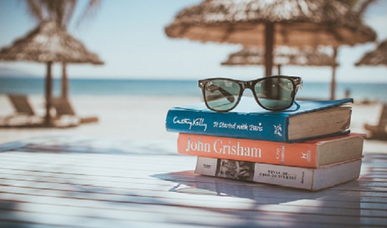 Libros y gafas de sol junto a una escena de viaje